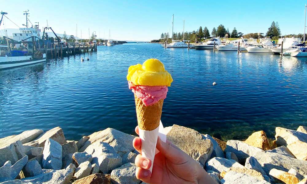 A person holding ice cream with a Bermagui view in the background